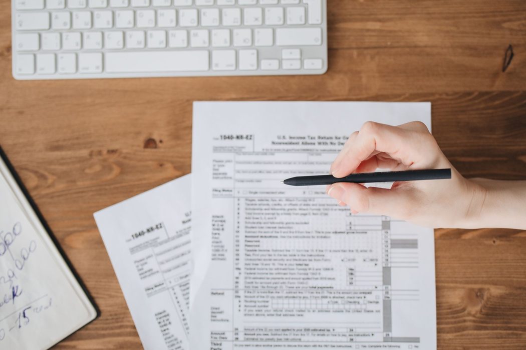 Person reviewing printed federal tax forms and a notebook at a desk